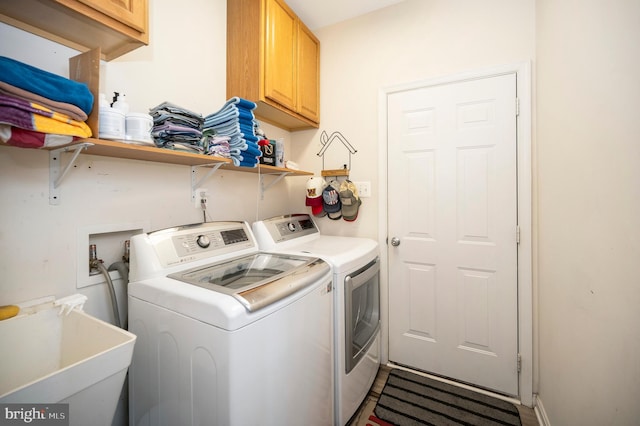 washroom with a sink, washing machine and clothes dryer, and cabinet space