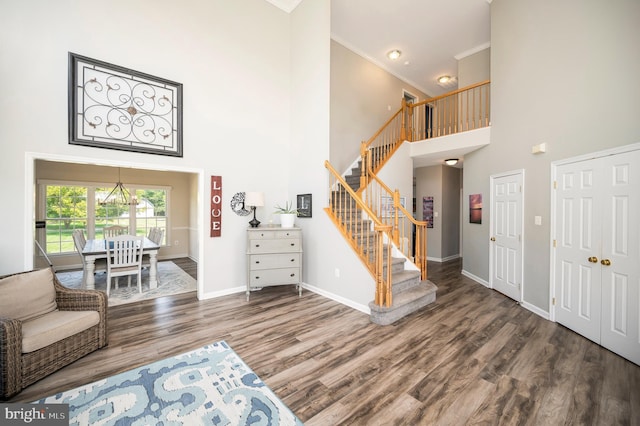 entryway featuring baseboards, stairway, wood finished floors, a high ceiling, and crown molding