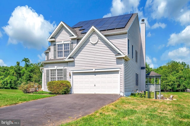 traditional home with a front yard, a chimney, aphalt driveway, and roof mounted solar panels