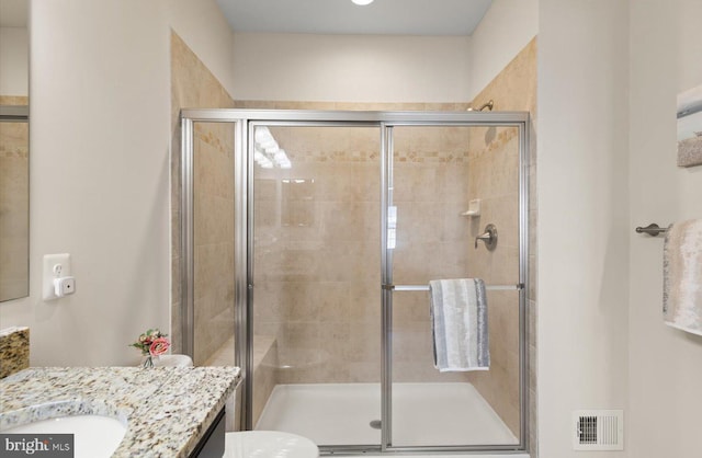 full bathroom with a stall shower, vanity, and visible vents