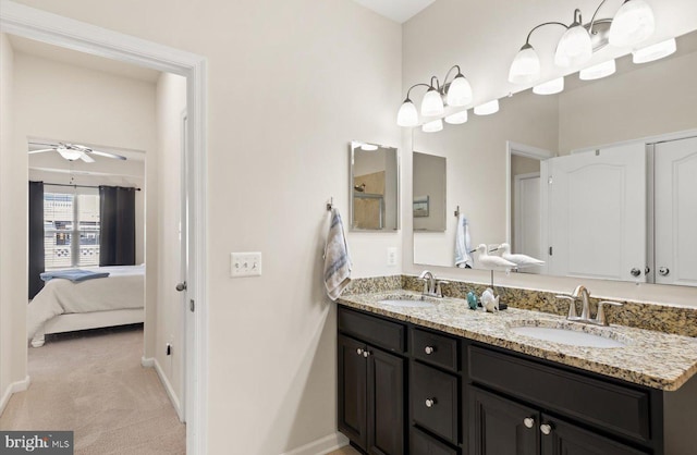 full bath with connected bathroom, a sink, baseboards, and double vanity