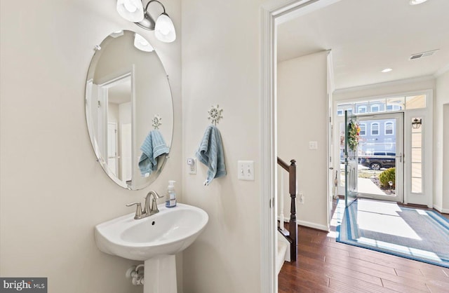 bathroom with a sink, baseboards, visible vents, and wood finished floors