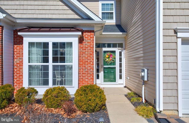 entrance to property with a garage and brick siding