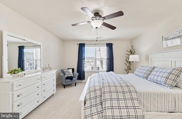 bedroom featuring light carpet, visible vents, multiple windows, and a ceiling fan