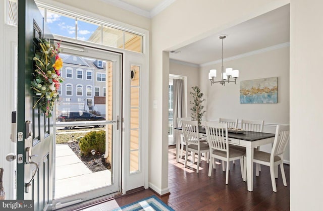 entrance foyer featuring dark wood-style floors, visible vents, crown molding, and an inviting chandelier