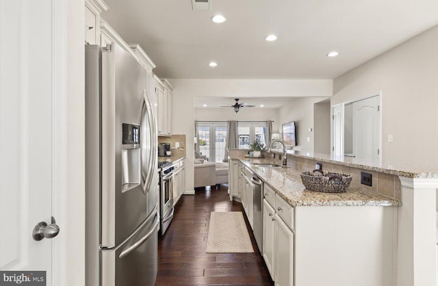 kitchen with a spacious island, appliances with stainless steel finishes, dark wood-type flooring, white cabinets, and a sink