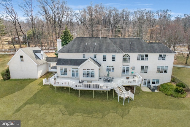 rear view of property featuring a chimney, french doors, a lawn, and a wooden deck