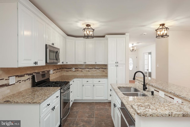 kitchen featuring a notable chandelier, appliances with stainless steel finishes, white cabinets, and a sink