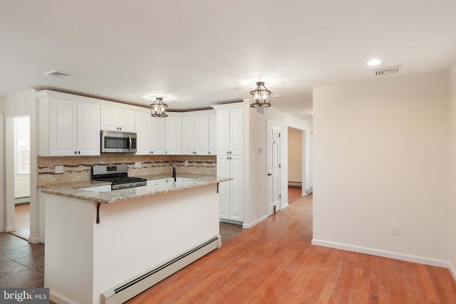 kitchen featuring stainless steel appliances, tasteful backsplash, a baseboard radiator, and white cabinetry