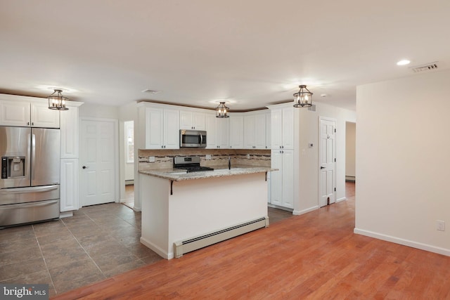 kitchen featuring white cabinets, visible vents, a baseboard heating unit, and stainless steel appliances