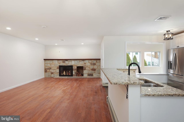 kitchen with stainless steel fridge, visible vents, light wood-type flooring, white cabinetry, and a sink