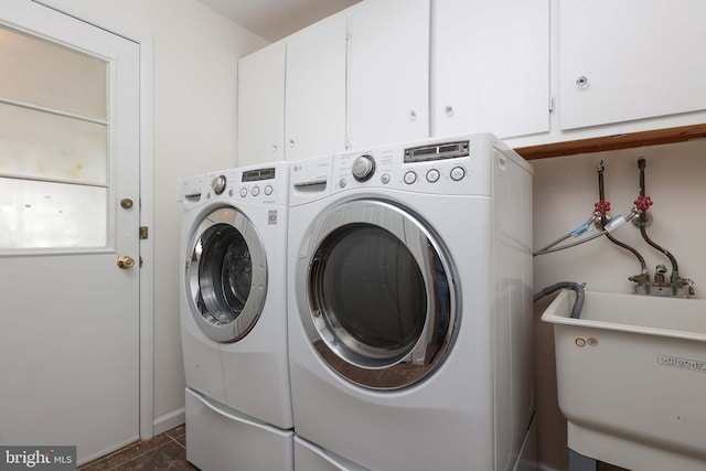 clothes washing area featuring separate washer and dryer, a sink, and cabinet space