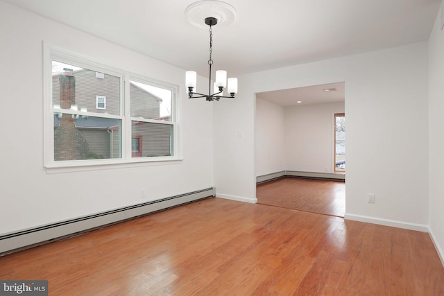 empty room with a baseboard radiator, baseboards, a notable chandelier, and light wood finished floors