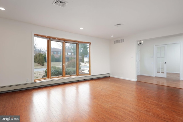 unfurnished room with baseboard heating, wood finished floors, visible vents, and recessed lighting