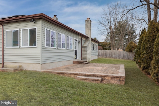 exterior space with a chimney, fence, a patio, and a lawn