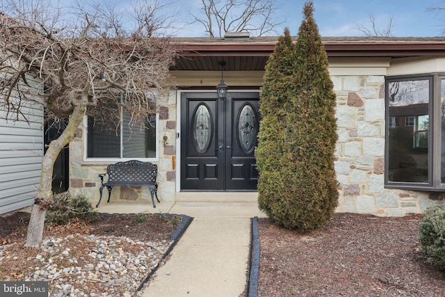 doorway to property with a porch and stone siding