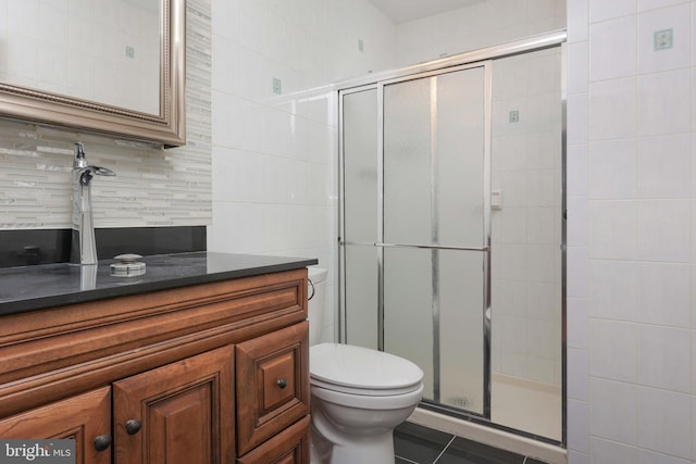 bathroom featuring toilet, a shower stall, decorative backsplash, and vanity