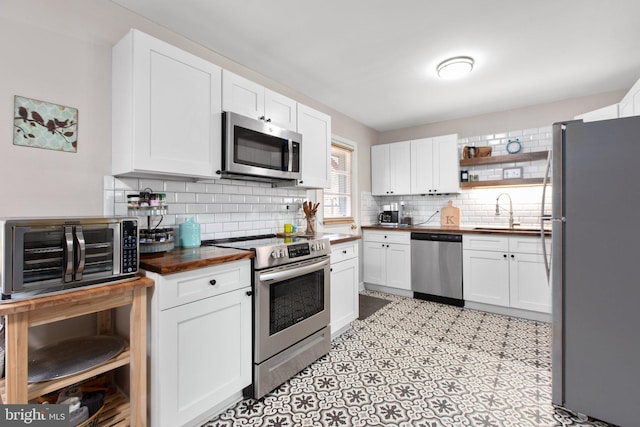 kitchen featuring white cabinets, tasteful backsplash, butcher block countertops, and stainless steel appliances