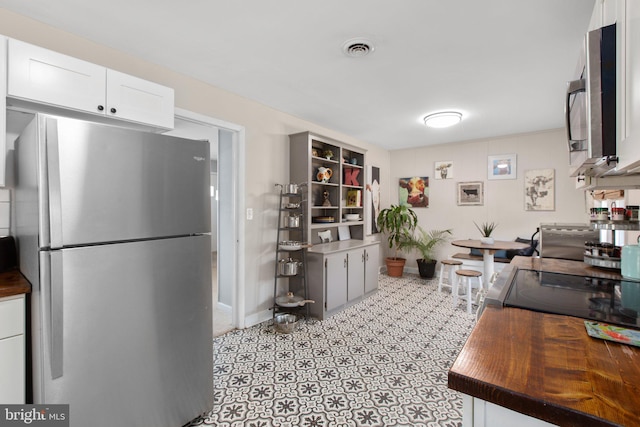 kitchen with butcher block countertops, visible vents, baseboards, white cabinetry, and appliances with stainless steel finishes