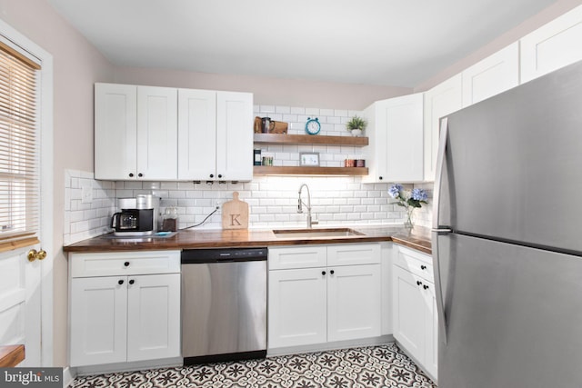 kitchen featuring open shelves, stainless steel appliances, backsplash, white cabinetry, and a sink