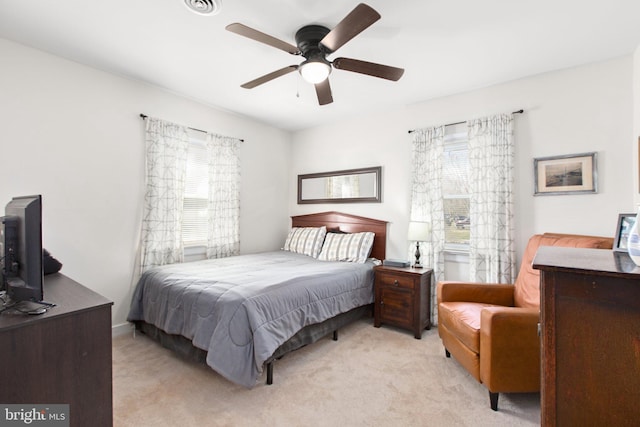 bedroom featuring multiple windows, a ceiling fan, and light colored carpet