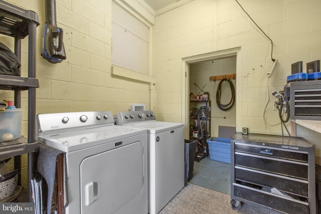 washroom featuring concrete block wall, laundry area, and washing machine and clothes dryer