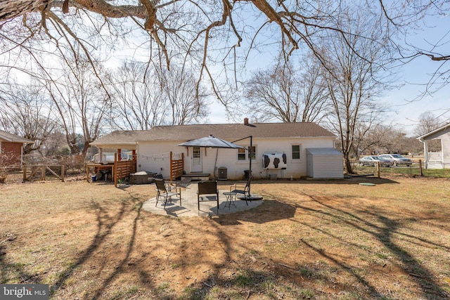 rear view of property featuring a patio, a chimney, a lawn, fence, and a wooden deck