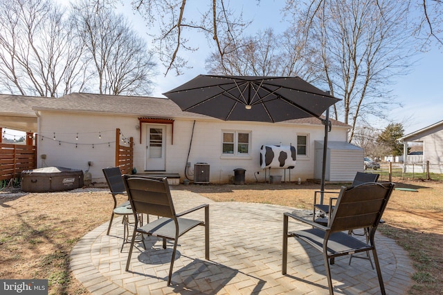 exterior space featuring cooling unit, a patio, a hot tub, and fence