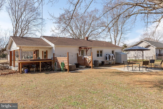 rear view of house with a patio, central AC unit, fence, a yard, and a chimney