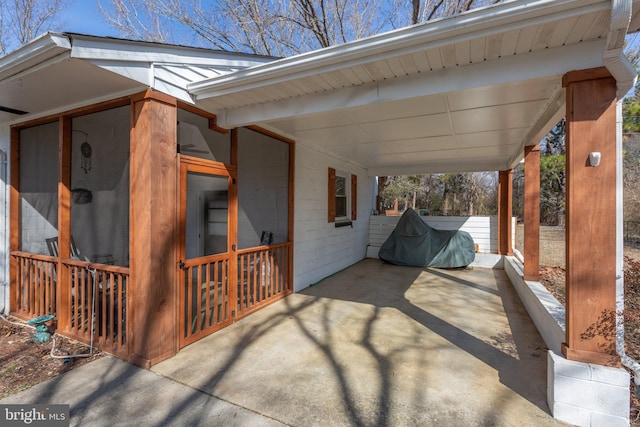 view of patio with driveway, a sunroom, and an attached carport