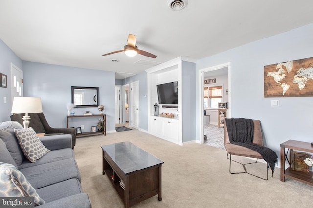 living room featuring a ceiling fan, visible vents, light carpet, and baseboards