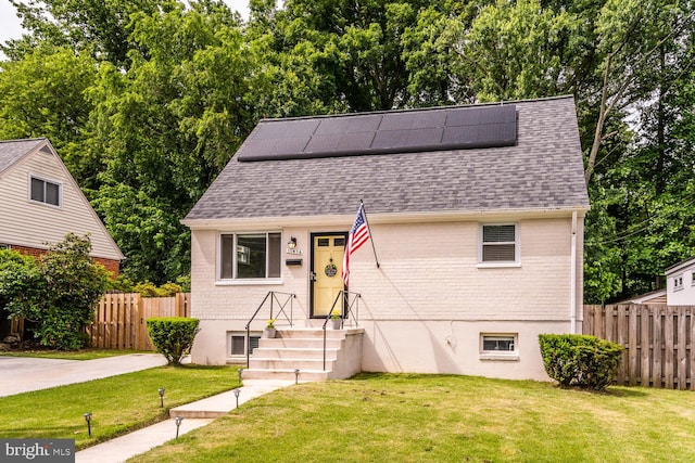 view of front of house with solar panels, brick siding, roof with shingles, and a front yard