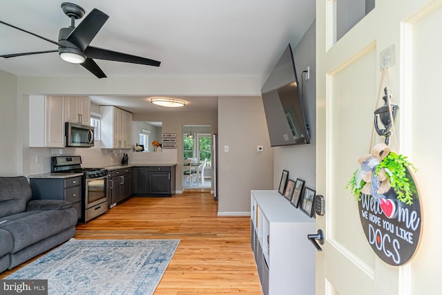 kitchen with tasteful backsplash, light wood-style flooring, appliances with stainless steel finishes, and light countertops