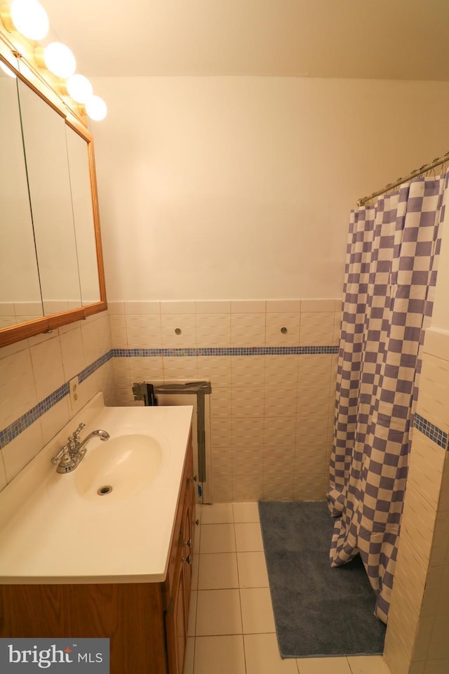 bathroom with a shower with shower curtain, a wainscoted wall, tile patterned floors, vanity, and tile walls