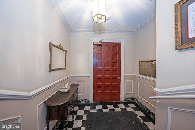 entryway with a decorative wall, a wainscoted wall, tile patterned floors, mail area, and crown molding