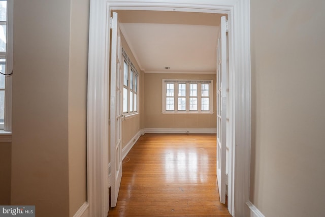 interior space with ornamental molding, light wood-type flooring, and baseboards