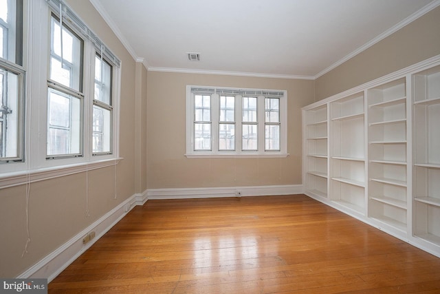 empty room with light wood-style floors, visible vents, plenty of natural light, and ornamental molding