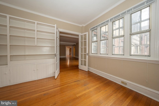 spare room with light wood-style floors, plenty of natural light, and crown molding