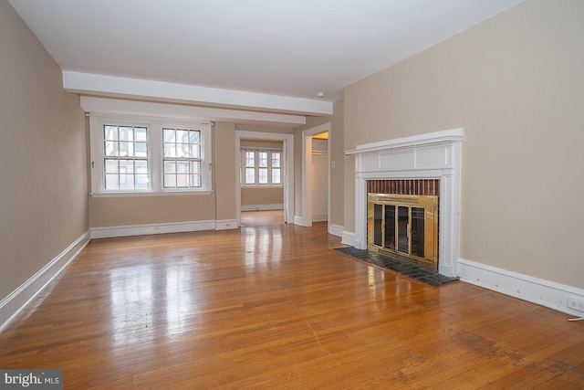 unfurnished living room with a baseboard radiator, a brick fireplace, hardwood / wood-style flooring, and baseboards