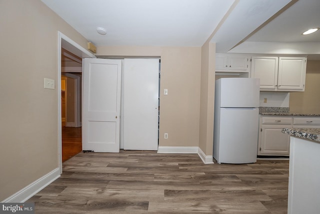 kitchen featuring freestanding refrigerator, white cabinets, dark wood finished floors, and baseboards