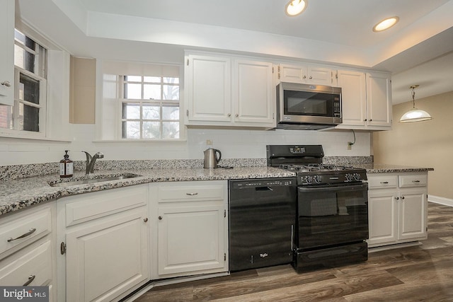 kitchen with a sink, white cabinetry, black appliances, a tray ceiling, and tasteful backsplash