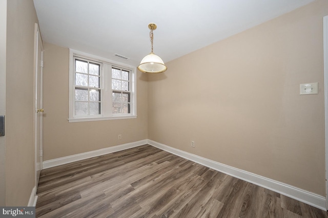 spare room with visible vents, baseboards, and wood finished floors