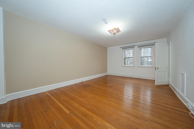 unfurnished room featuring visible vents, light wood-style flooring, and baseboards