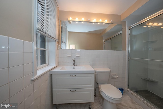 full bathroom with a stall shower, tile walls, vanity, and tile patterned floors