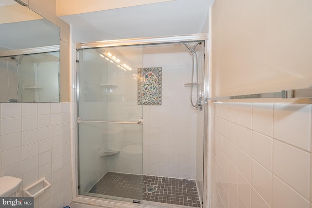 full bathroom featuring toilet, a shower stall, and tile walls