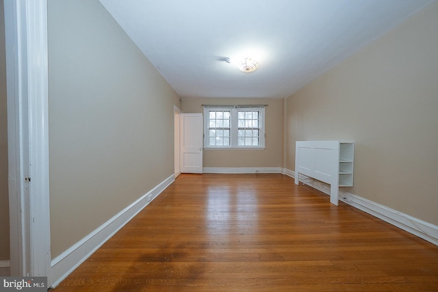 spare room with baseboards and wood finished floors