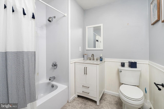 full bathroom featuring vanity, wainscoting, shower / bath combo with shower curtain, and toilet