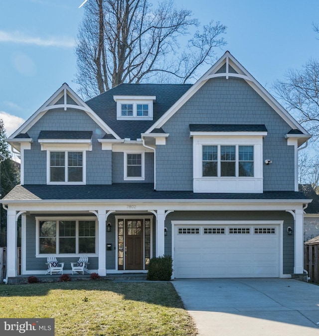 view of front facade with a front lawn, roof with shingles, driveway, and an attached garage