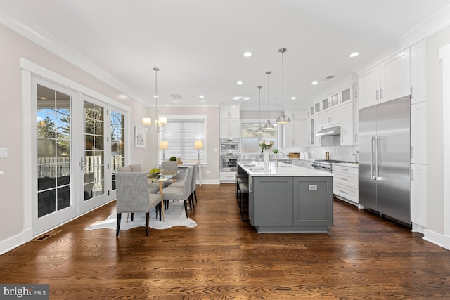 kitchen with white cabinets, light countertops, under cabinet range hood, and built in refrigerator