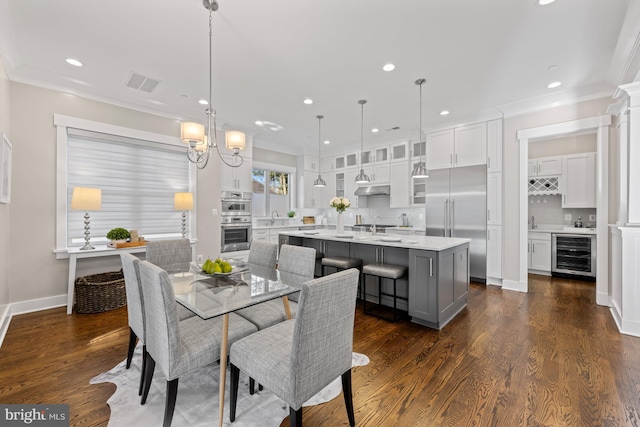 dining room featuring beverage cooler, visible vents, dark wood finished floors, and crown molding